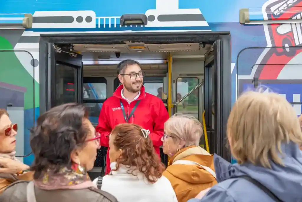 Guía turístico de TEM Turistik recibiendo a un grupo de pasajeros en la puerta de un autobús.