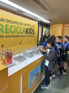 Niños escolares participan en una actividad de reciclaje en el mostrador del bus ReciclaKids de TEM Turistik.