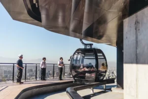 Cabina de teleférico llegando a la estación Pío Nono con pasajeros y personal de TEM Turistik supervisando.