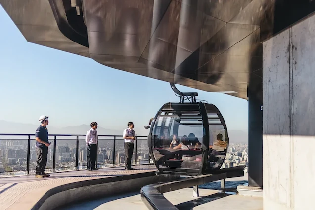 Cabina de teleférico llegando a la estación Pío Nono con pasajeros y personal de TEM Turistik supervisando.