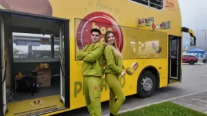 Pareja con outfits verdes posa frente a un bus de dos pisos amarillo de TEM Turistik con branding Bon o Bon y pistachos.
