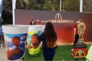 Personas interactuando en un stand temático de la Copa Mundial con vasos gigantes y la copa en un evento de TEM Turistik.