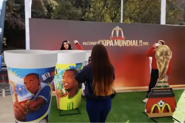 Personas interactuando en un stand temático de la Copa Mundial con vasos gigantes y la copa en un evento de TEM Turistik.