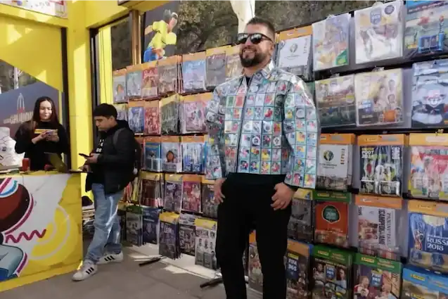 Hombre usando una chaqueta creativa decorada con láminas y autoadhesivos frente a un stand de coleccionables en TEM Turistik