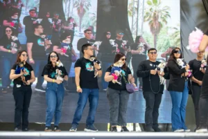 Grupo de personas sostiene a sus perros pequeños en un escenario durante un evento de ParquePet, con pantalla grande de fondo